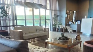 A modern hotel lobby with a brown leather sofa, a glass coffee table, and a reception desk.