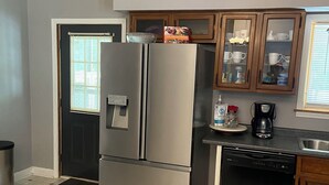 Une cuisine équipée d’un réfrigérateur en acier inoxydable, d’un lave-vaisselle et de meubles de rangement en bois.