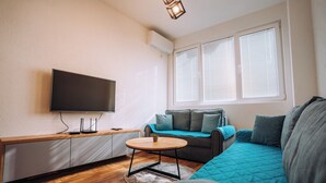 A modern living room with a flat-screen TV, a sofa, a coffee table, and a window with blinds. - Luxury Lake Nearby Free Parking Pet Friendly APT (Ohrid)