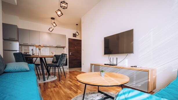 A modern living room with a sofa, a round coffee table, and a TV mounted on the wall. - Luxury Lake Nearby Free Parking Pet Friendly APT (Ohrid)
