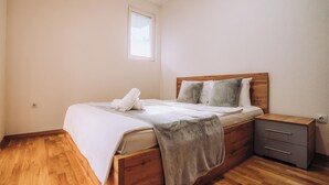 A bedroom with a wooden bed, a nightstand, a window, and a wooden floor. - Luxury Lake Nearby Free Parking Pet Friendly APT (Ohrid)