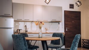 A modern kitchen with white cabinets, a wooden dining table, and four blue chairs. - Luxury Lake Nearby Free Parking Pet Friendly APT (Ohrid)