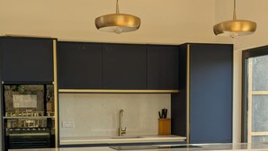 Uma cozinha moderna com armários azul-escuros, bancada branca e dois bancos de madeira.