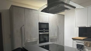 A modern kitchen with a central island, built-in oven, and a microwave. - Charming Austrian Home Near Hallstatt - Perfect Base for Your Salzburg Getaway (Attnang-Puchheim)