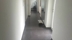 A hallway with dark tiled flooring, white walls, and doors leading to rooms. - Charming Austrian Home Near Hallstatt - Perfect Base for Your Salzburg Getaway (Attnang-Puchheim)