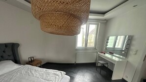 A bedroom with a bed, a desk, a chair, a large window, and a hanging light fixture. - Charming Austrian Home Near Hallstatt - Perfect Base for Your Salzburg Getaway (Attnang-Puchheim)