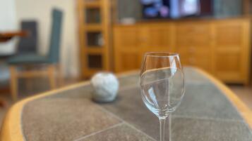 Un bicchiere di vetro trasparente su un tavolo piastrellato, con una televisione sullo sfondo.