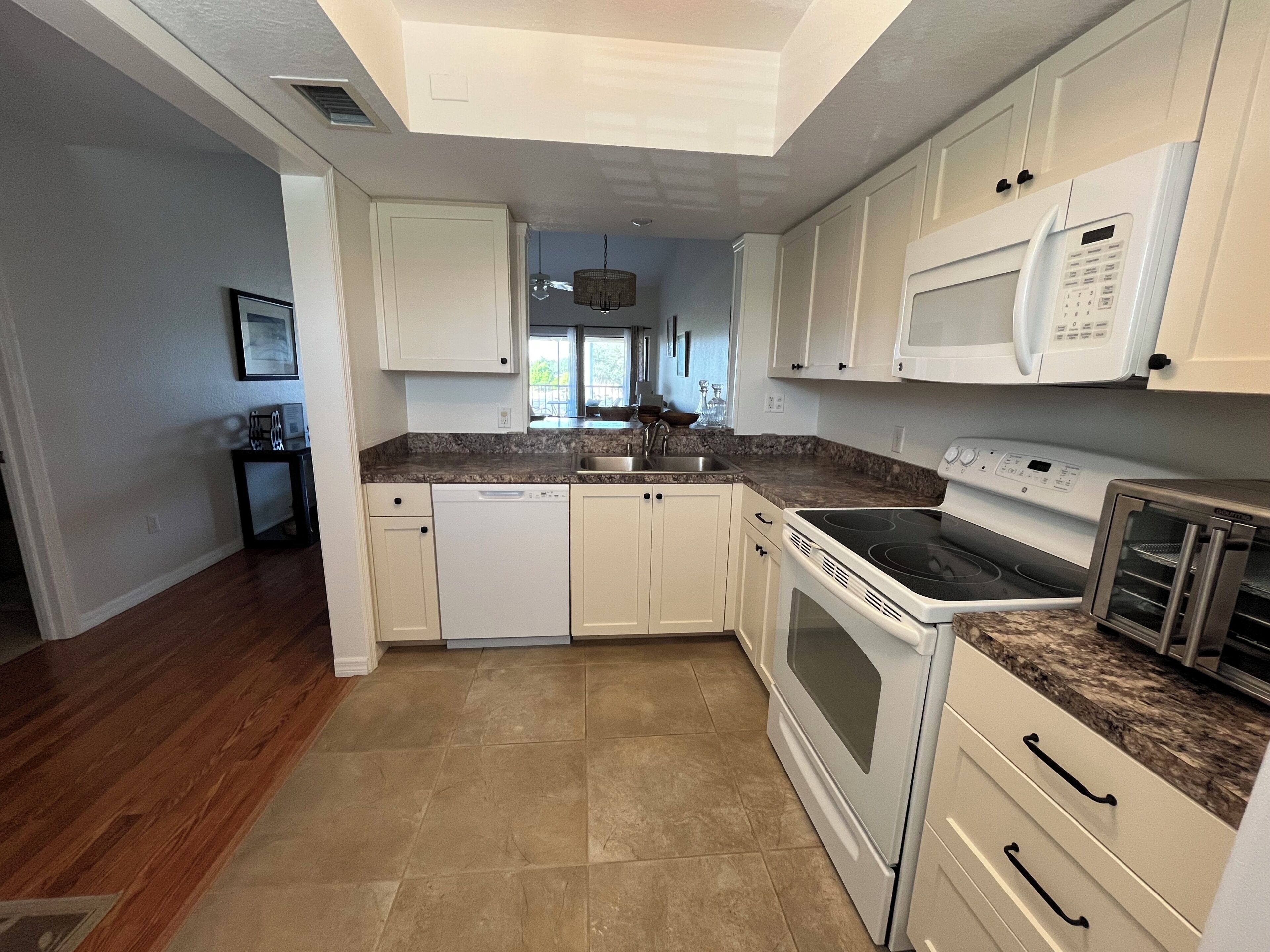 A kitchen with white cabinets, a dishwasher, a stove, and a microwave.