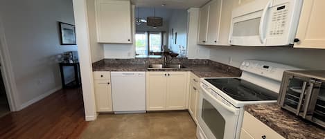 A kitchen with white cabinets, a dishwasher, a stove, and a microwave.