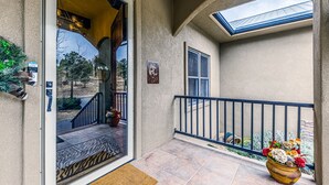 A covered outdoor area with a glass door leading inside, a small balcony with a railing, and a welcome sign. - Toasted Marshmallows | Luxury Cabin in Ruidoso w/ Hot Tub & Game Room (Ruidoso)