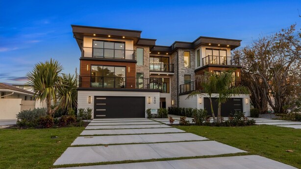 A modern two-story house with a garage, large windows, and a well-maintained lawn. - Lido Luxe Estate: Large Rental Steps to the Beach with Pool, Spa, Outdoor Games (Lido Key)