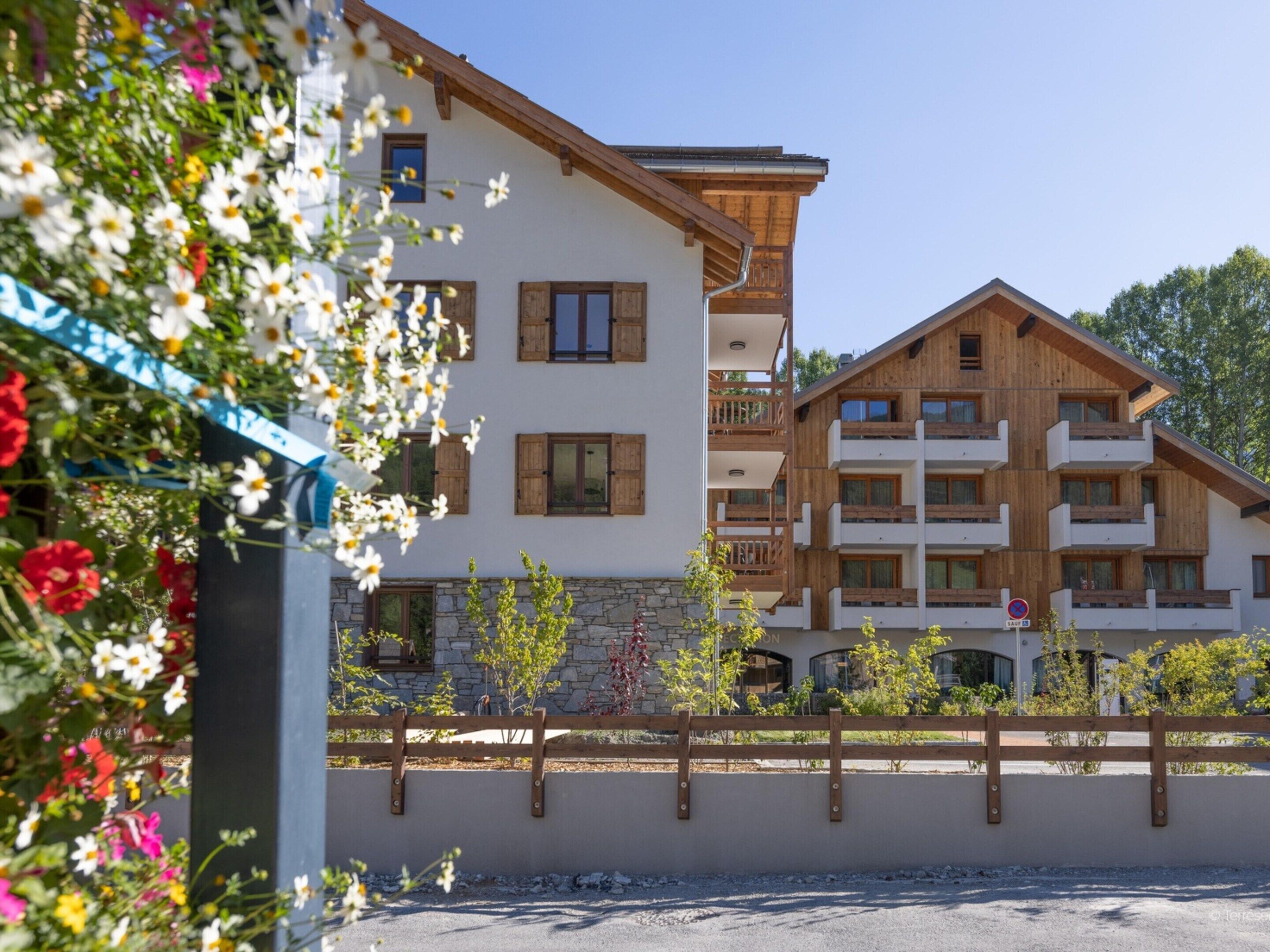A multi-story building with balconies, a stone foundation, and a wooden facade.