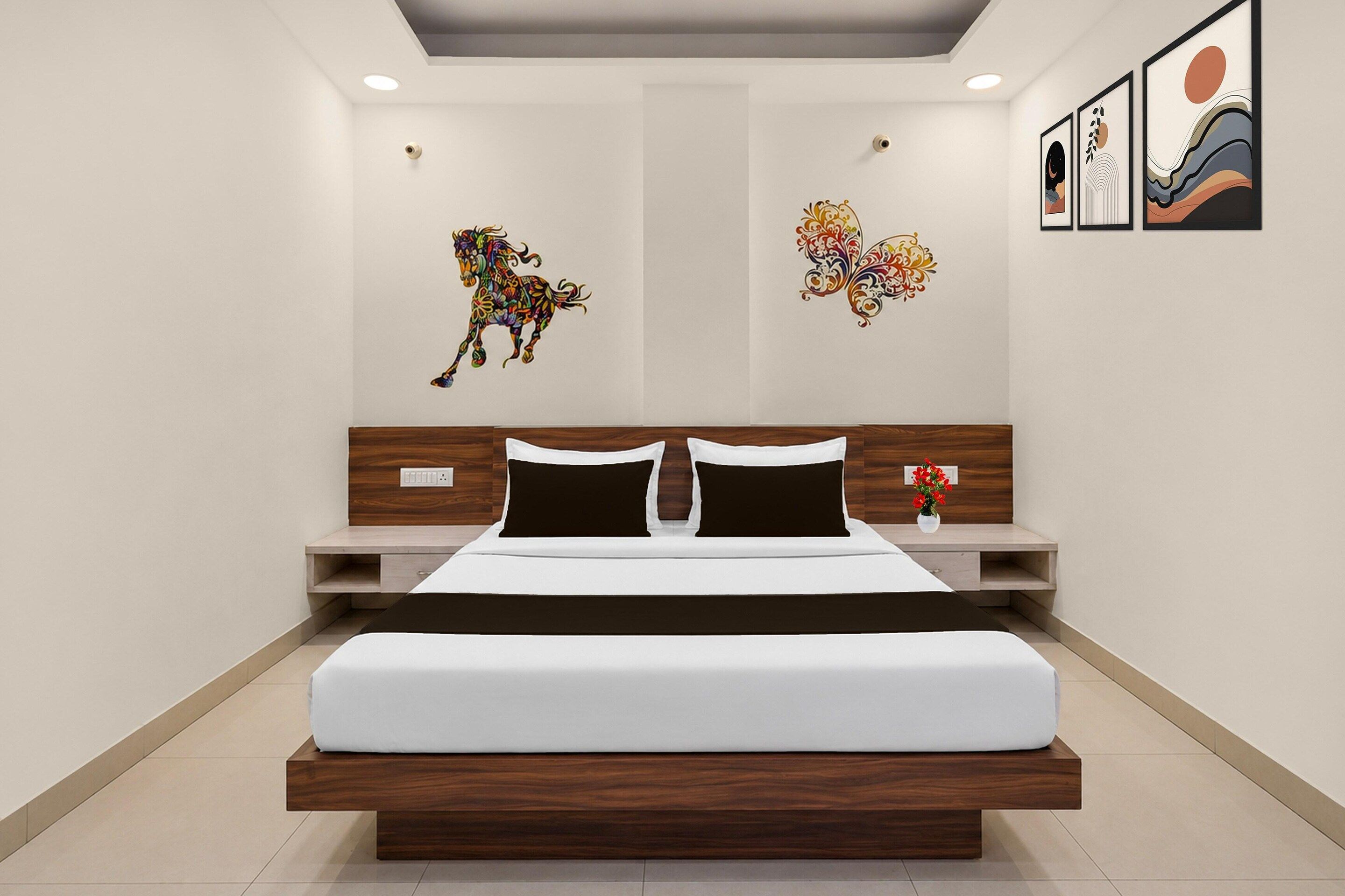 A modern bedroom with a large bed, wooden headboard, bedside tables, and wall art.