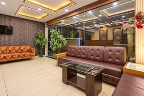 A modern lobby with a sofa, a coffee table, and a TV mounted on the wall. - Super Townhouse Hoshangabad Road Near Aashima Mall (Bhopal)