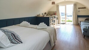 A bedroom with a bed, a small kitchenette, a chair, and a view of the outdoors. - Torsa (Oban)