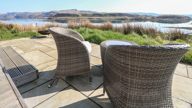 Wicker patio furniture with a view of a lake and hills in the background. - Torsa (Oban)