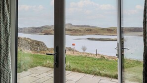 Vista attraverso una porta di vetro su un paesaggio collinare e un corso d'acqua.