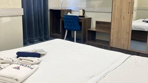 A hotel room with a bed, a desk, a chair, a TV, and an air conditioning unit. - Premium 777 (Tashkent)