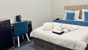 A hotel room with a bed, a desk, a chair, and a small refrigerator. - Premium 777 (Tashkent)