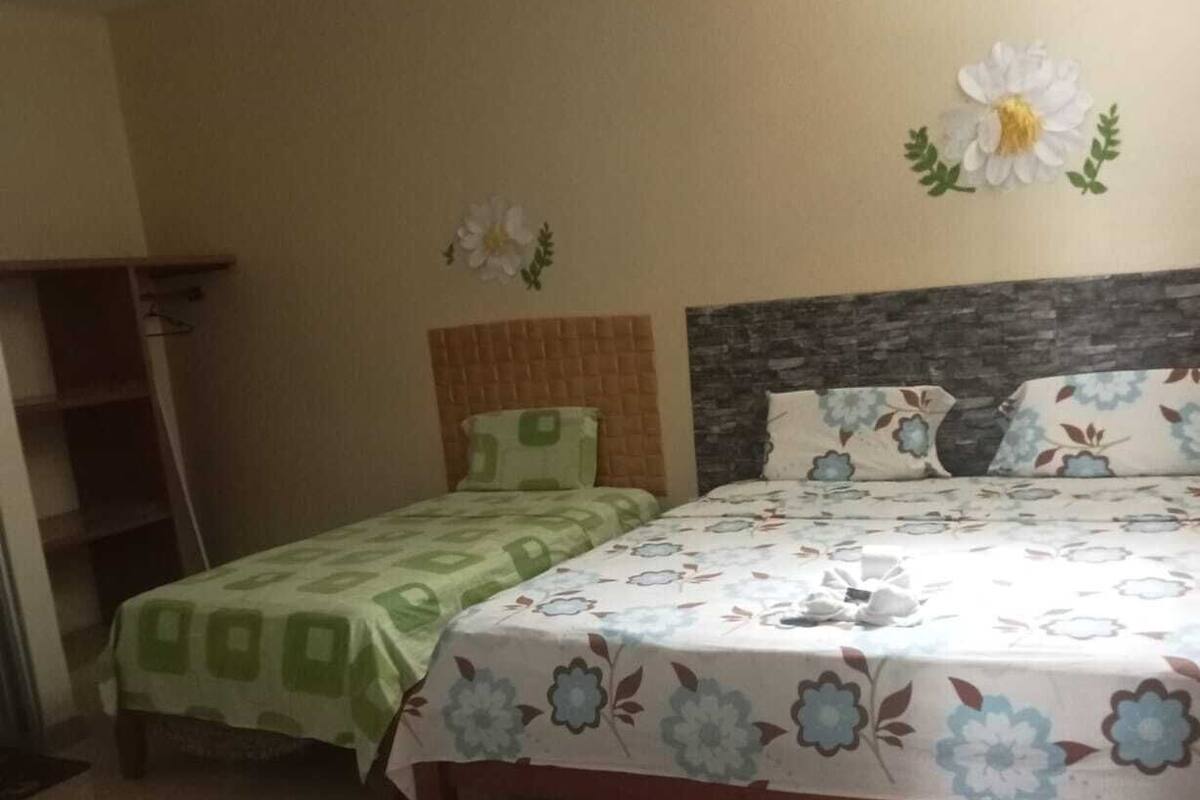 A bedroom with two beds, a wooden headboard, and a tiled floor.