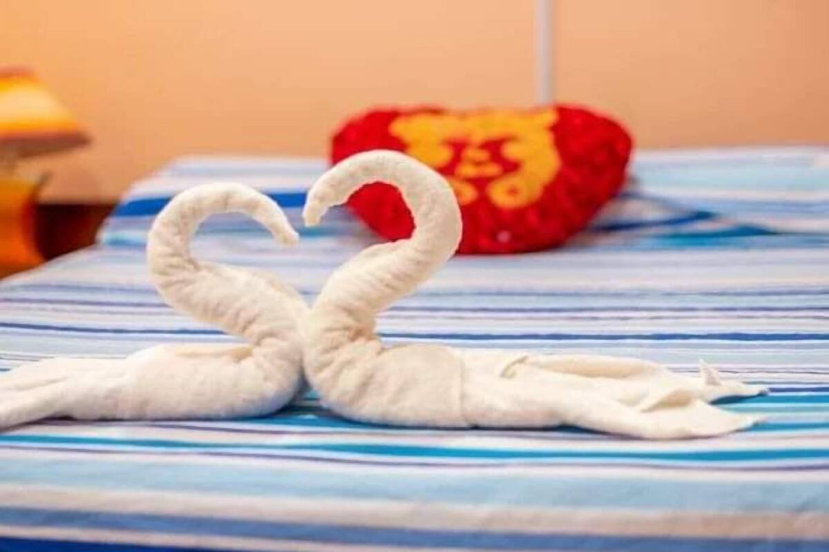 A bed with a blue and white striped bedspread and a red pillow with a golden emblem.