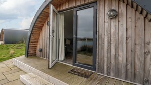 Een modern, gebogen houten gebouw met een glazen deur en een klein buitengebied met treden.