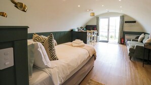 Een slaapkamer met een bed, een bank, een bureau en uitzicht op het omliggende landschap.