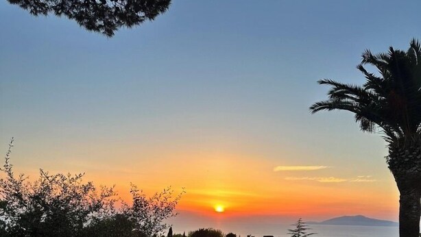 An outdoor dining table set for a meal with a sunset view. - La Canostra Capri - luxury villa (Anacapri)