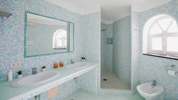 A bathroom with two sinks, a mirror, a shower, and a window.