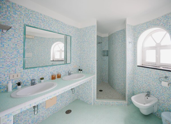 Une salle de bain avec deux lavabos, un miroir, une douche et une fenêtre.