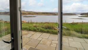 A view from a room with a glass door, overlooking a lake and surrounding landscape. - Losal (Oban)