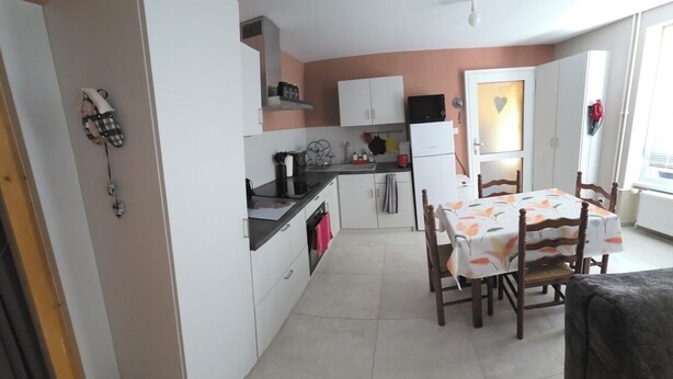 Una cocina compacta con muebles blancos, una mesa de comedor con sillas y un ventanal con vistas.