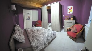 Un dormitorio con una cama, una silla, un armario y una puerta que da a otra habitación.