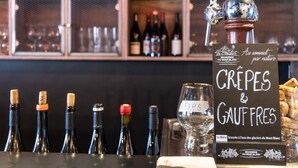 Eine Bar mit einem Schild, auf dem "CRÈPES & GAUFRES" steht, und einer Flasche "La Biere" auf der Theke.