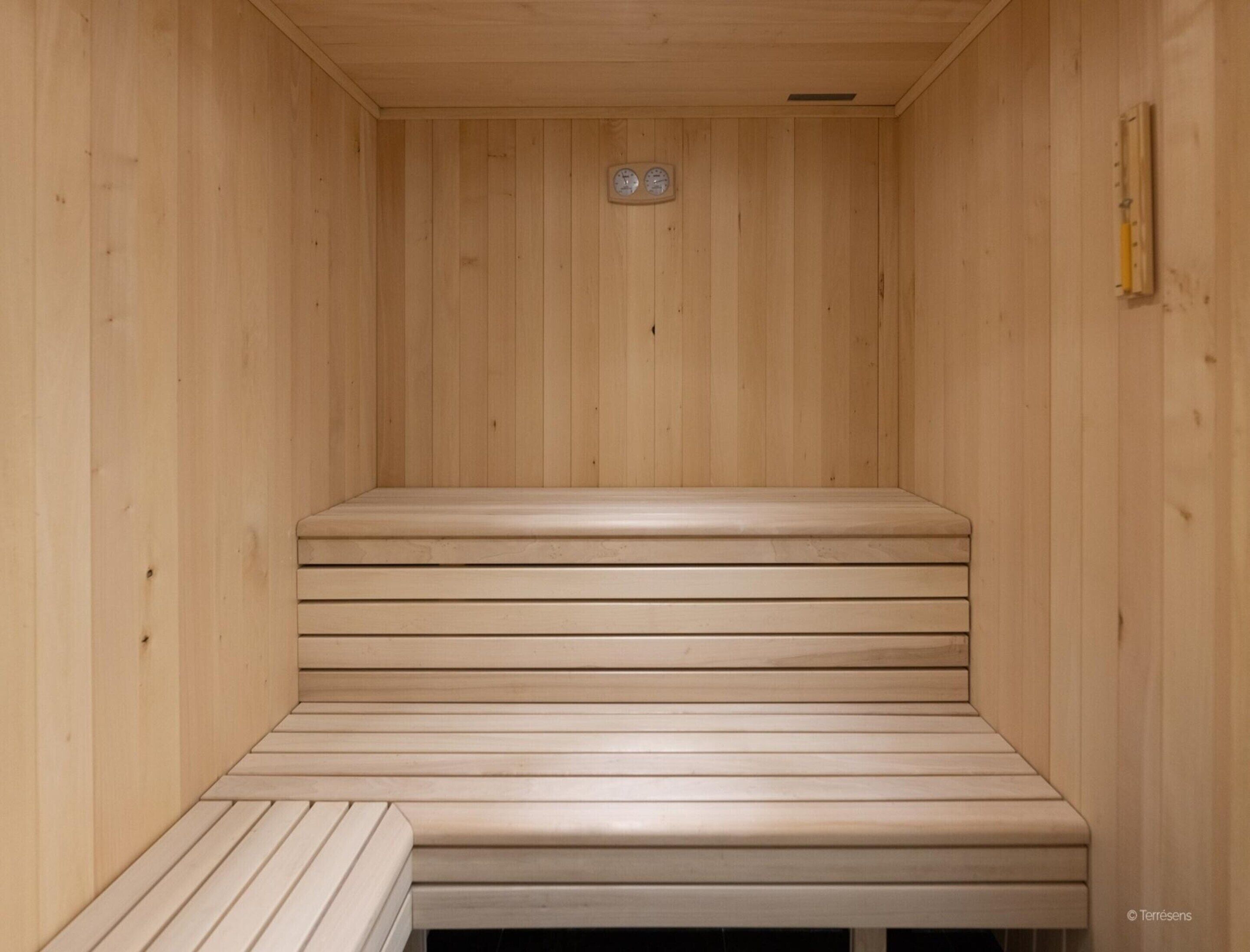 Un sauna en bois, doté de bancs et d’une horloge fixée au mur.
