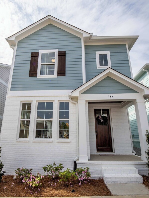 Stunning two-story home with a charming front entrance, complete with a dark brown door and white-framed windows.
