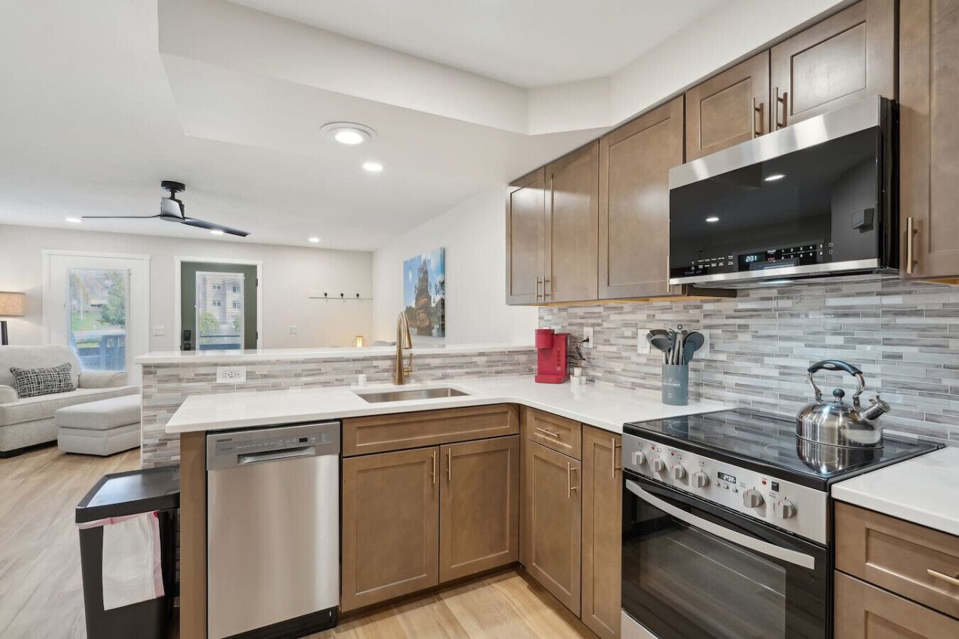 A modern kitchen with wooden cabinets, stainless steel appliances, and a tiled backsplash.