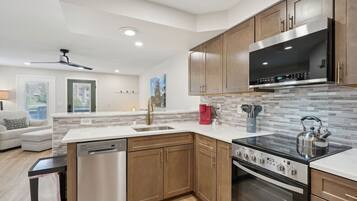 A modern kitchen with wooden cabinets, stainless steel appliances, and a tiled backsplash.