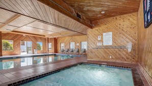 A large indoor swimming pool with wooden walls and ceiling, clear glass doors leading outside, and a tiled floor. - Pine Needle 506 at Lighthouse Cove (Wisconsin Dells)