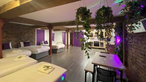 Ein Hotelzimmer mit zwei Betten, einem Esstisch und hängenden Pflanzen.