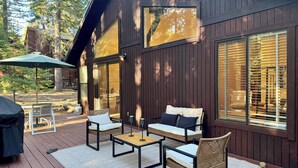 A wooden deck with outdoor furniture, including a sofa and chairs, and a table.