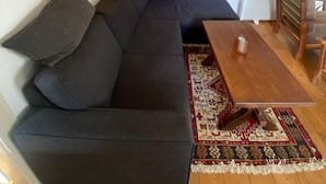Un soggiorno moderno con un divano angolare grigio scuro, un tavolino in legno e un tappeto decorato.