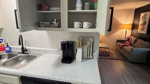 Une cuisine compacte équipée d’un lave-vaisselle, d’une machine à café et d’un four à micro-ondes.