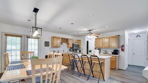 A modern kitchen with wooden cabinets, a central island, and a dining area with a wooden table and chairs. - Spacious & Charming Poconos Pine Hideaway (Tobyhanna)