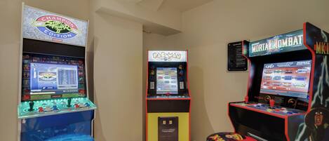 A room with arcade machines including Pac-Man, Street Fighter II, and Mortal Kombat.