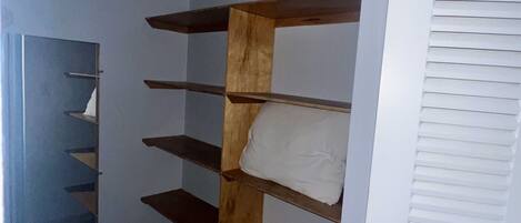 A closet with wooden shelves and a white door with louvered panels.