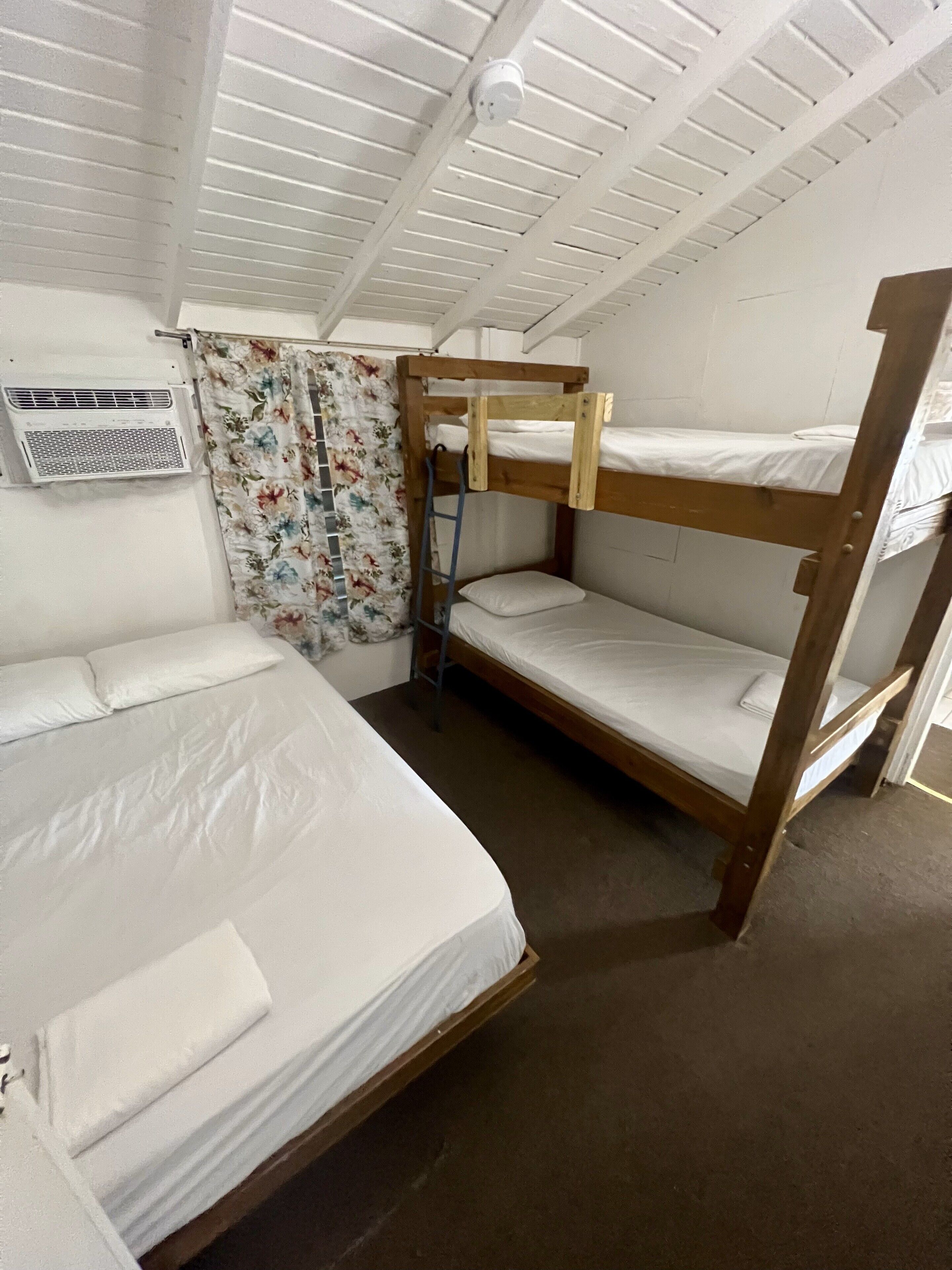 A bunk bed room with a window, a curtain, and an air conditioning unit.