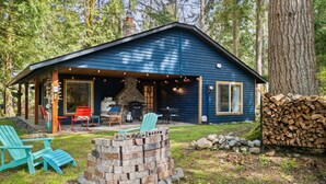 A cabin with a covered patio, outdoor seating, and a stone fire pit.