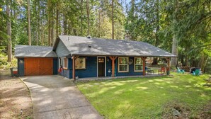 A two-story house with a garage, a covered porch, and a well-maintained lawn.