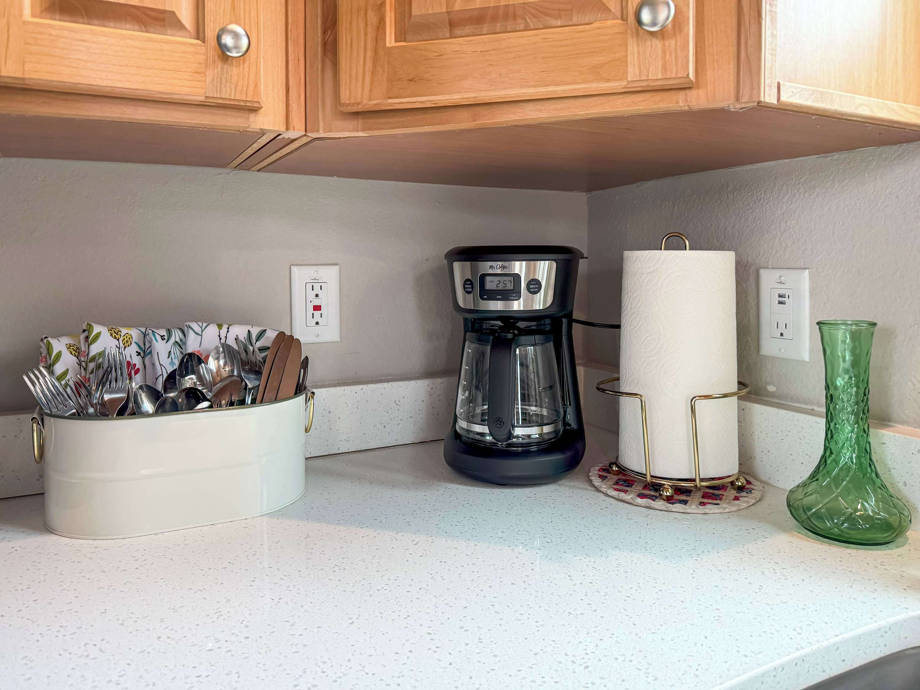 A kitchen counter with a coffee maker, a paper towel holder, and a utensil holder.